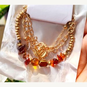 Layered gold-tone bracelet with warm amber glass beads and a leaf charm — Sira Elegance